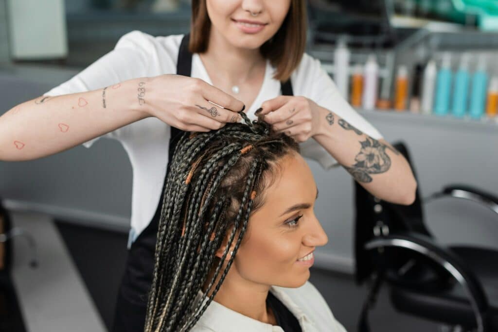 beauty industry,braids,tattooed hairdresser braiding hair of woman in salon,braiding process,